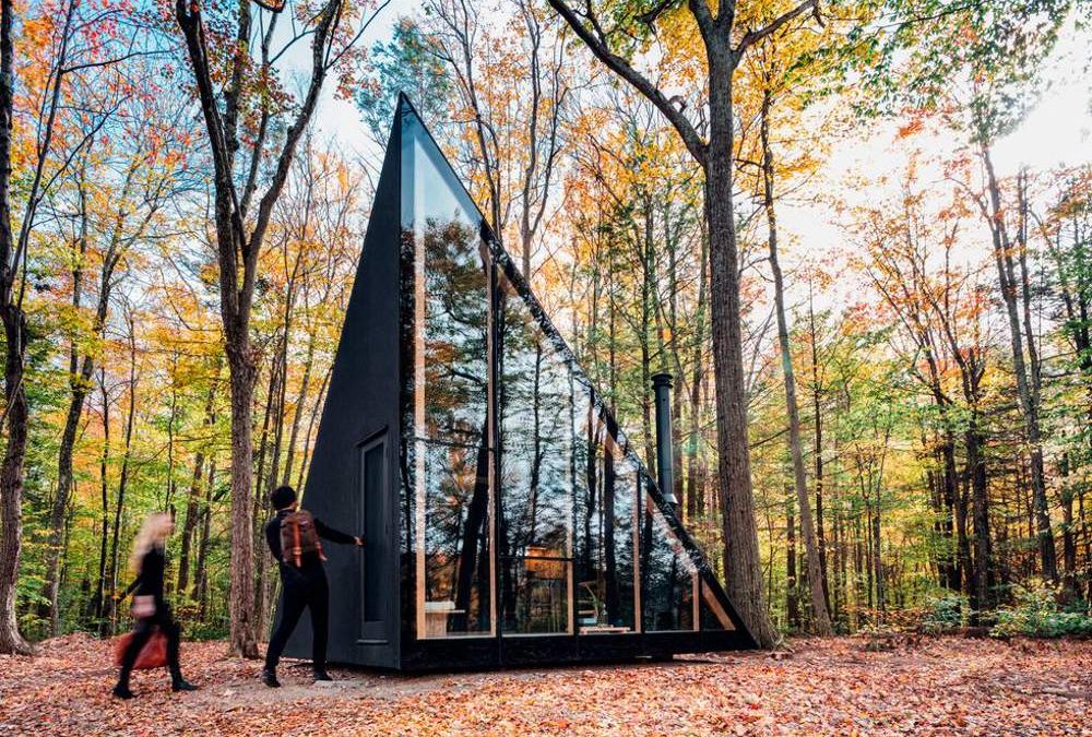 Una casa de vidrio y madera con forma de tienda de campaña